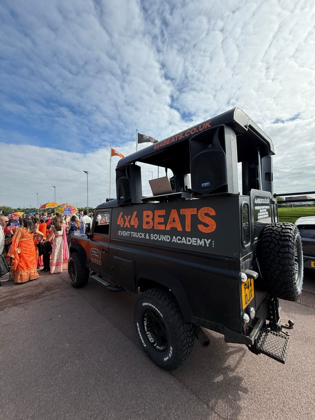 Rear view of the 4x4 Beats event truck at an Asian wedding procession with guests and umbrellas